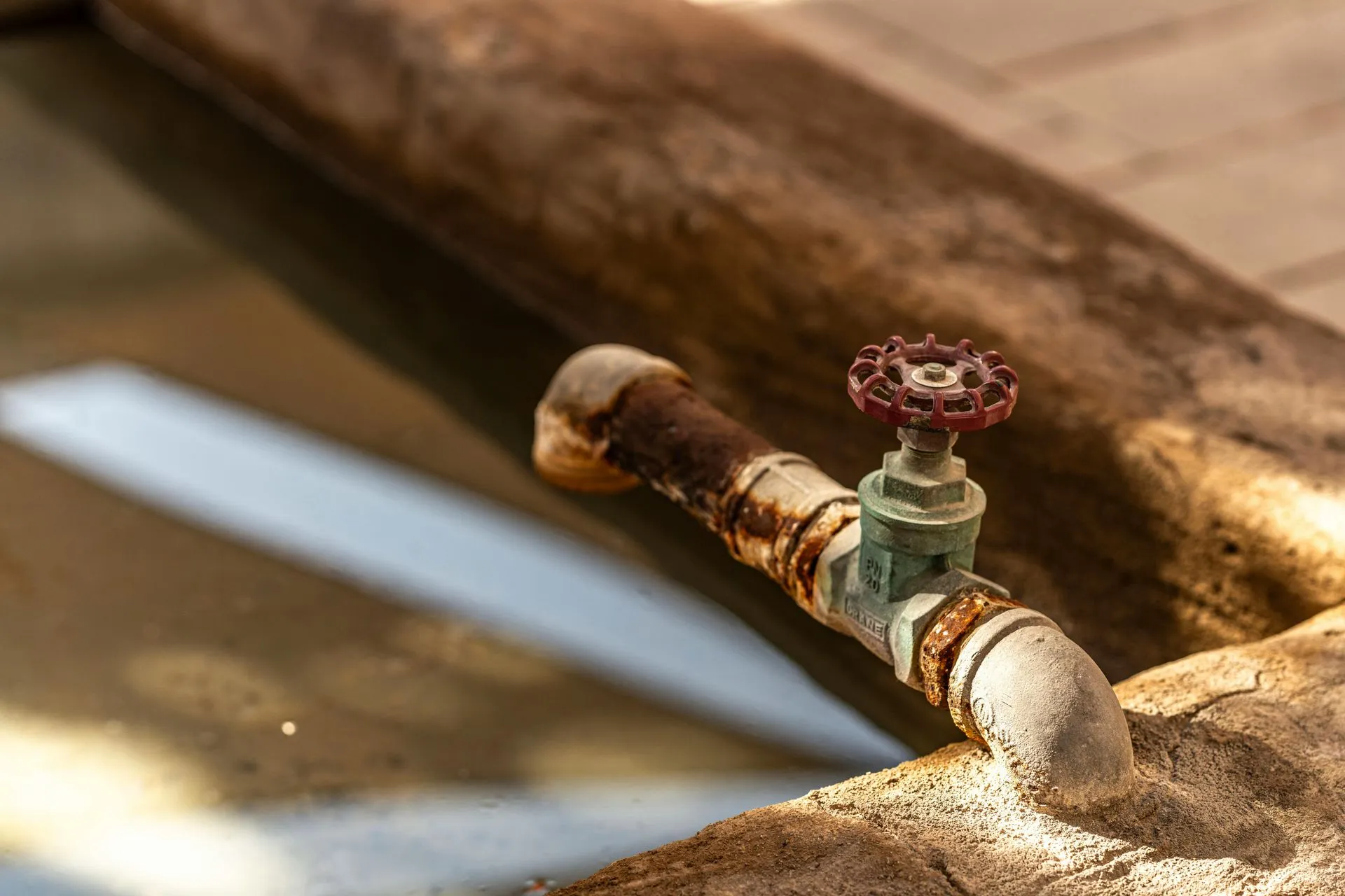 Rusty old water pipe with a red-handled valve