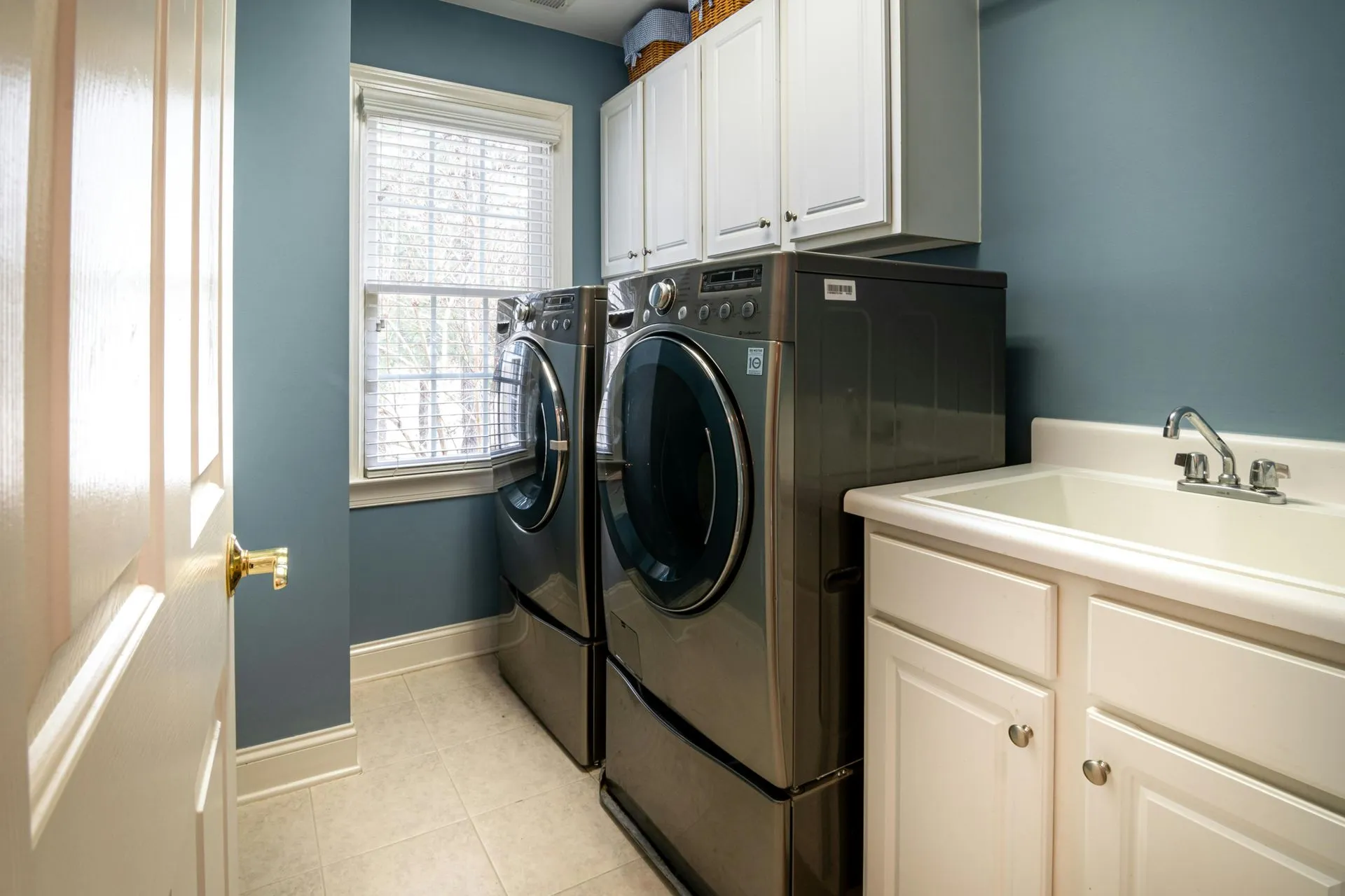 Laundry room with a white utility sink, cabinets and a front-load washer and dryer